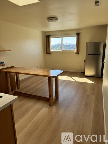 A kitchen with a table and a refrigerator.