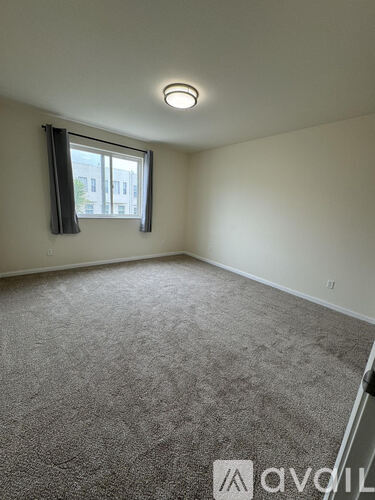 A room with a carpeted floor and a window with a view of a building outside.