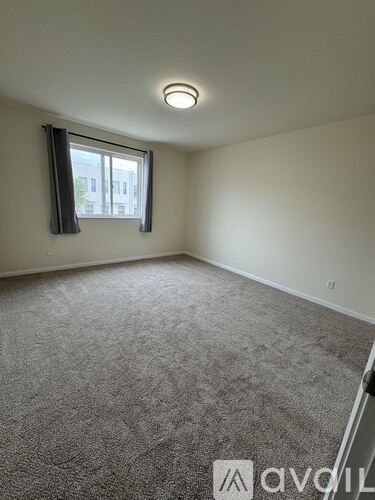 A room with a carpeted floor and a window with a view of a building outside.