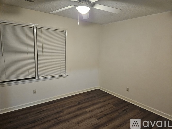 A room with a ceiling fan and wooden flooring.