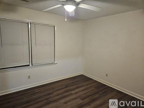 A room with a ceiling fan and wooden flooring.