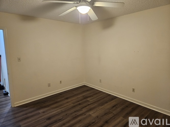 A room with a ceiling fan and wooden flooring.