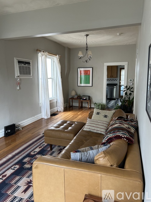 A living room with a tan couch and a rug with a pattern.