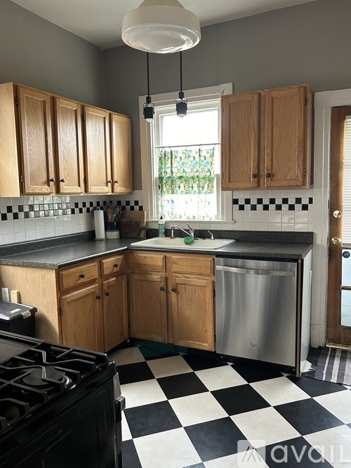 A kitchen with wooden cabinets and a black and white checkered floor.