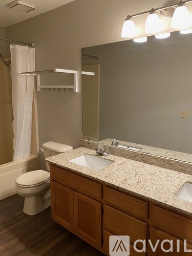 A bathroom with a toilet, sink, and mirror.