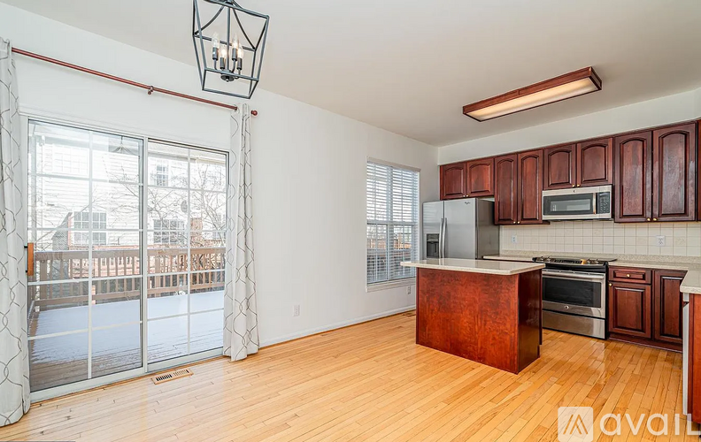 A kitchen with wooden cabinets and a large window overlooking a snowy landscape.