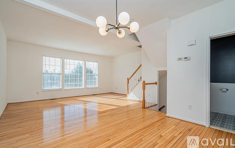 A spacious room with wooden floors and a staircase leading to another room.