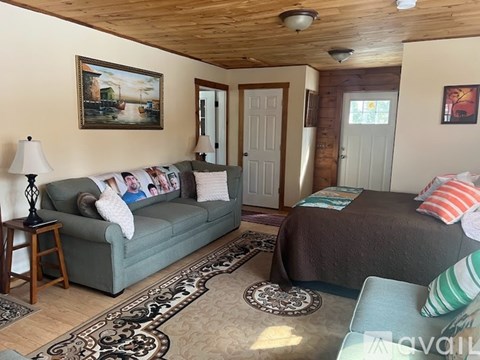 A living room with a green couch and a bed with striped pillows.