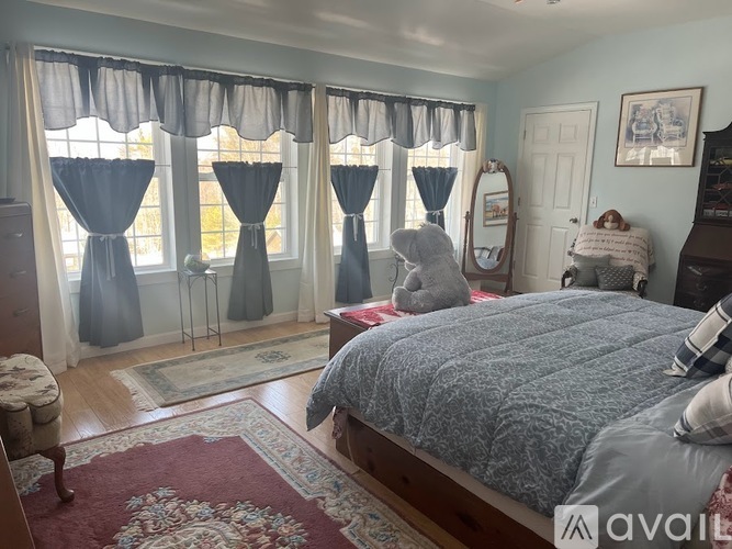 A bedroom with a large bed and a window with curtains.