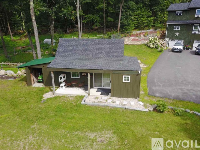 A house with a green roof and a porch is surrounded by a grassy yard.