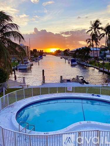 A sunset view from a pool with boats in the background.