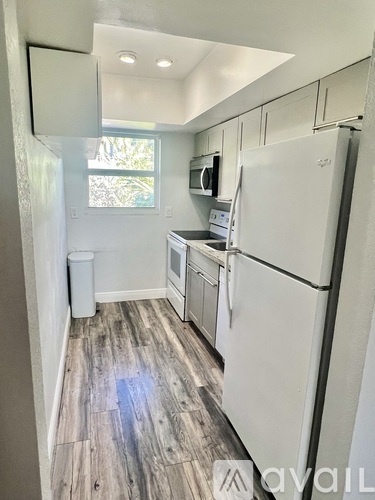 A kitchen with white appliances and wood flooring.