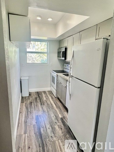 A kitchen with white appliances and wood flooring.