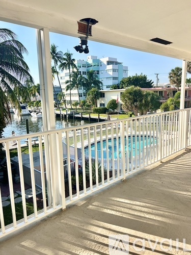 A white balcony with a pool and palm trees in the background.