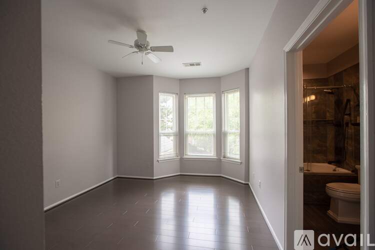 A spacious room with a ceiling fan and sliding glass doors leading to a bathroom.