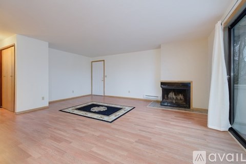 A living room with a fireplace and a rug on the floor.
