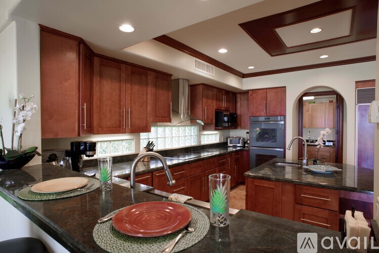 A kitchen with brown cabinets and a black countertop.