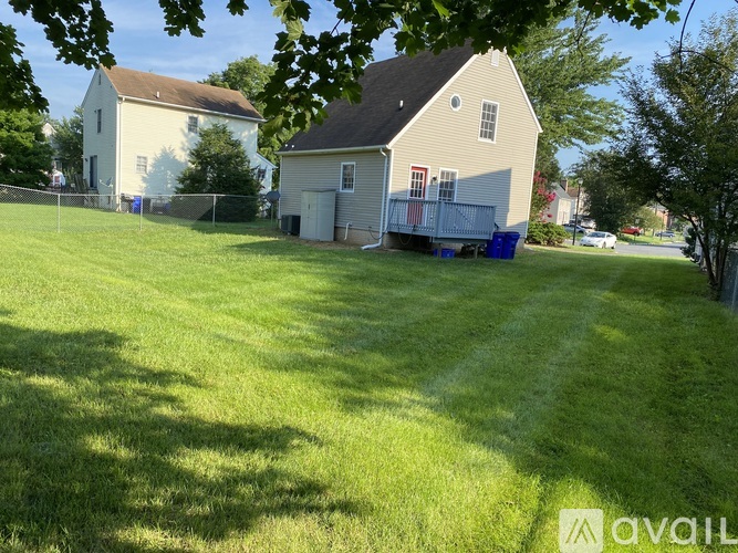 A house with a white fence and a blue trash bin in front.