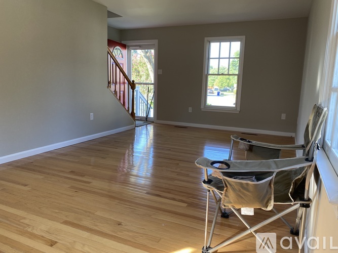 A living room with a wooden floor and a chair.