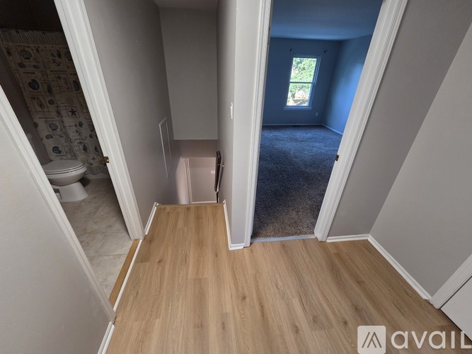 A room with a wooden floor and a window with a view of trees.