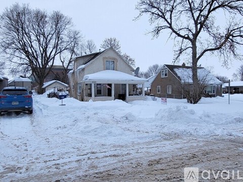 A car is parked in front of a house with a snow-covered ground.