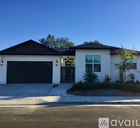 A white house with a black garage door is available for sale.