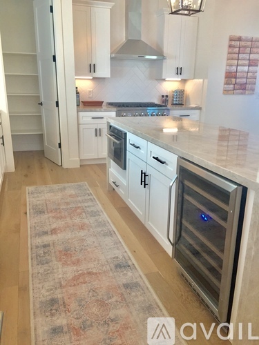 A kitchen with a rug on the floor and a refrigerator on the left.