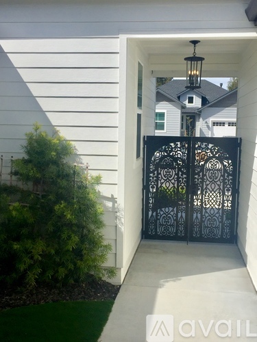 A black wrought iron gate leads to a house.