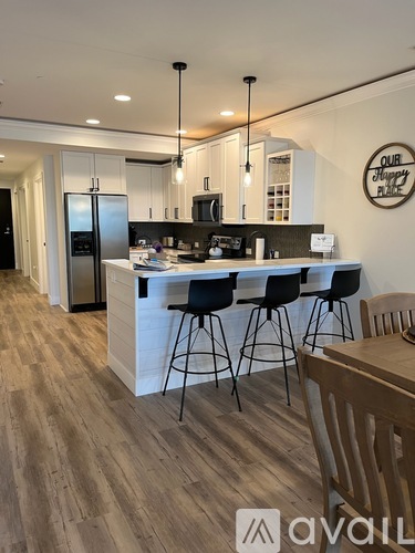 A modern kitchen with wooden floors and a white island.