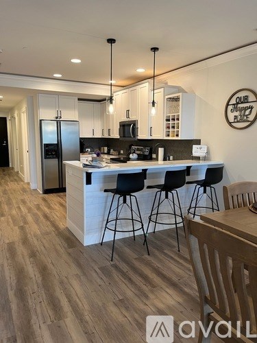 A modern kitchen with wooden floors and a white island.