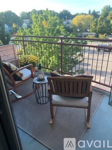 A balcony with a chair and a table with flowers on it.