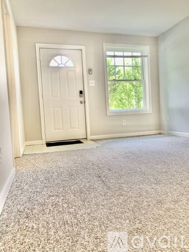 A room with a carpeted floor, a door, and a window.