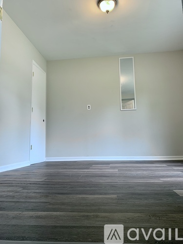 A room with a wooden floor and a mirror on the wall.