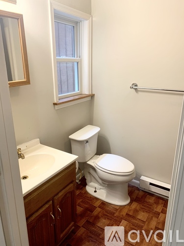 A white toilet sits in a bathroom next to a sink and a window.