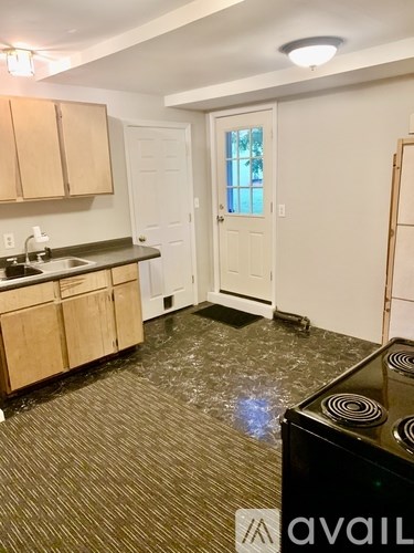 A kitchen with a black stove top oven and a white door.
