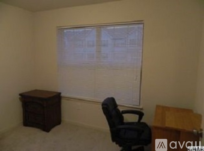 A room with a desk, chair, and window with blinds.