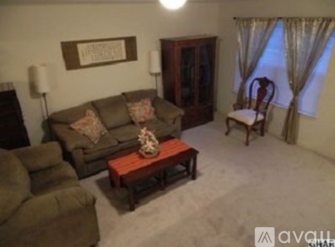A living room with a brown couch, a wooden coffee table, and a chair.