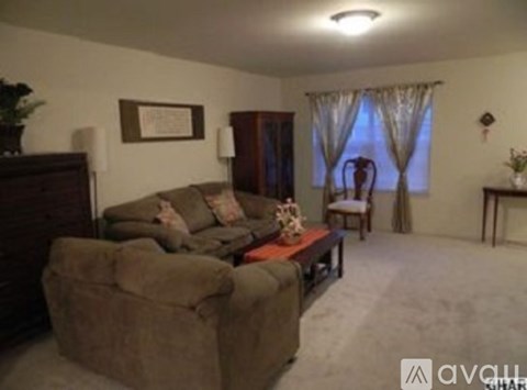 A living room with a brown couch and a wooden cabinet.