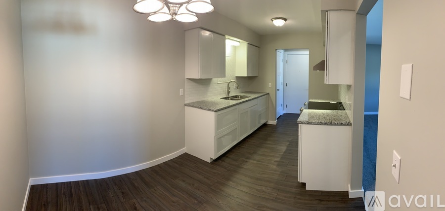 A kitchen with white cabinets and a wooden floor.