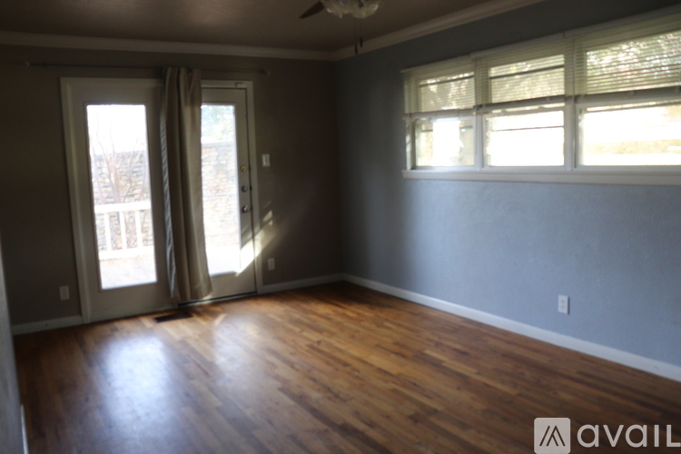 A room with wooden floors and a window with blinds.