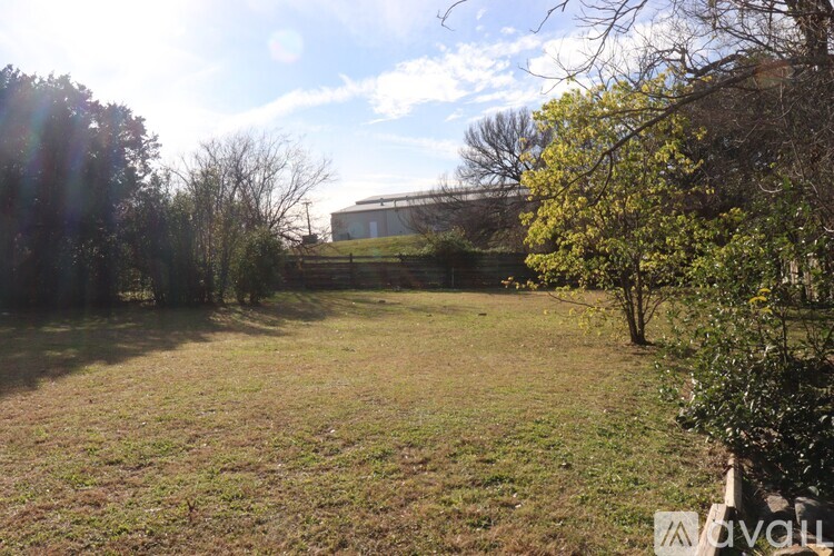 A field with trees and a building in the background.
