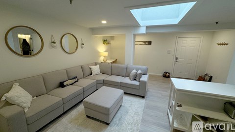 A living room with a grey sofa and a skylight.