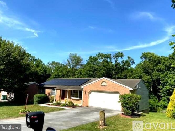 A house with a garage and a driveway is surrounded by greenery.