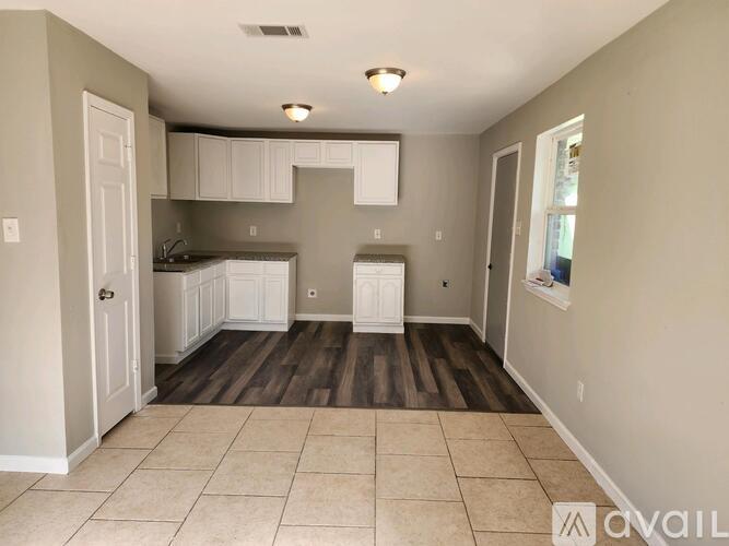 A kitchen area with white cabinets and a tiled floor.