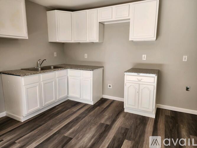 A kitchen with white cabinets and a wooden floor.