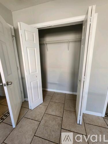 A white closet with a door open and a hanger in it.