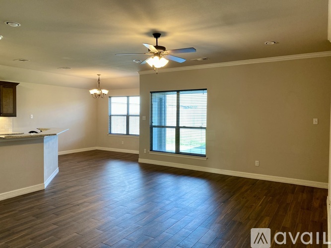 A spacious room with wooden flooring and a ceiling fan.