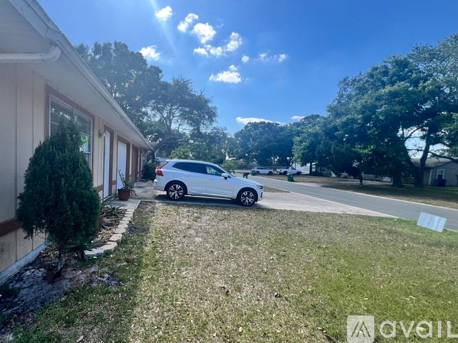A white car is parked in a driveway next to a house.