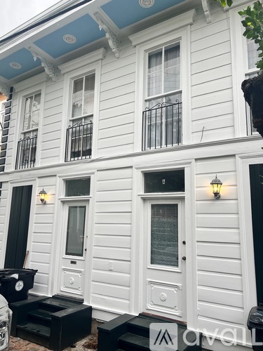A white house with black railings and a black awning.