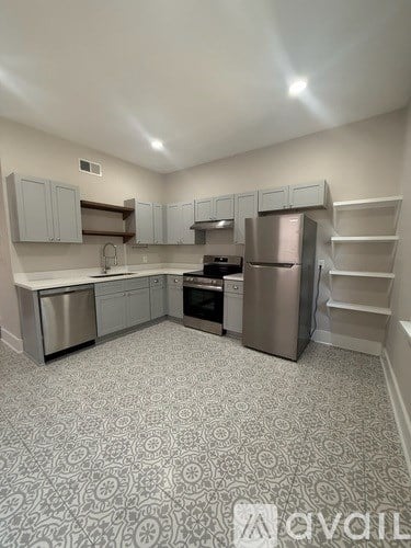A kitchen with a patterned floor and stainless steel appliances.
